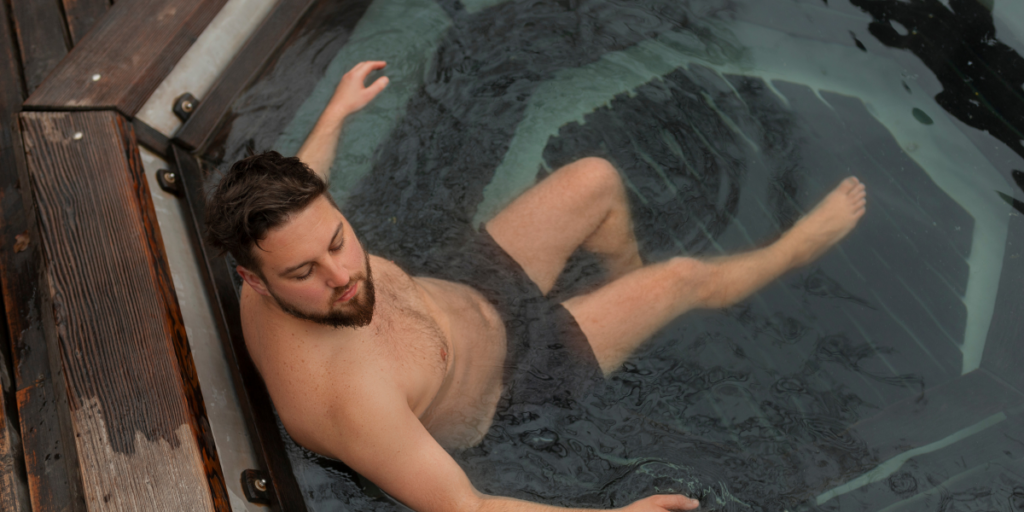 A man wearing shorts relaxing in a hot tub, enjoying the warm water and peaceful surroundings.